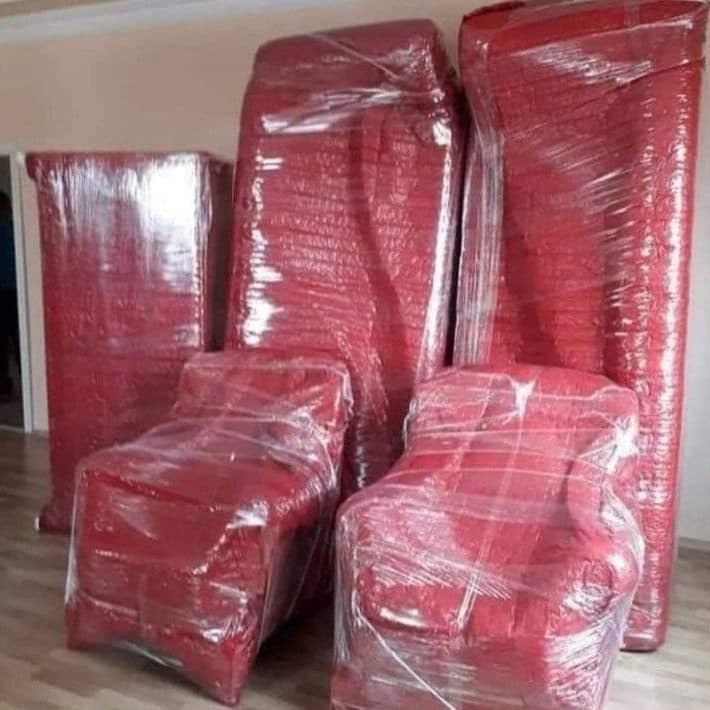 Mattresses and armchairs padded in red protective material and stretch wrap before loading